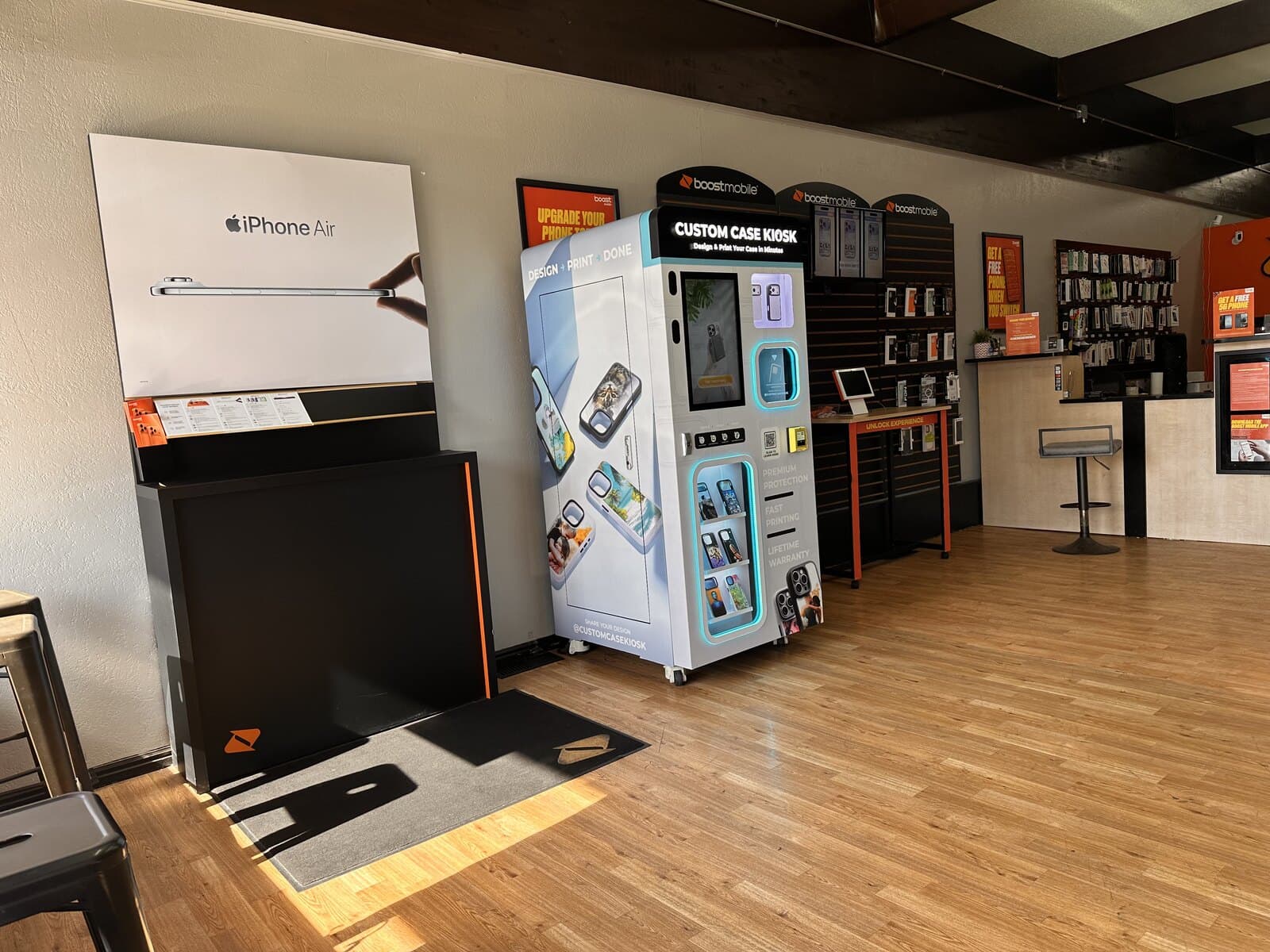 The Custom Case Kiosk inside the Boost Mobile store on 3900 South in Salt Lake City, standing against the wall beneath the Boost Mobile signage beside the accessory display