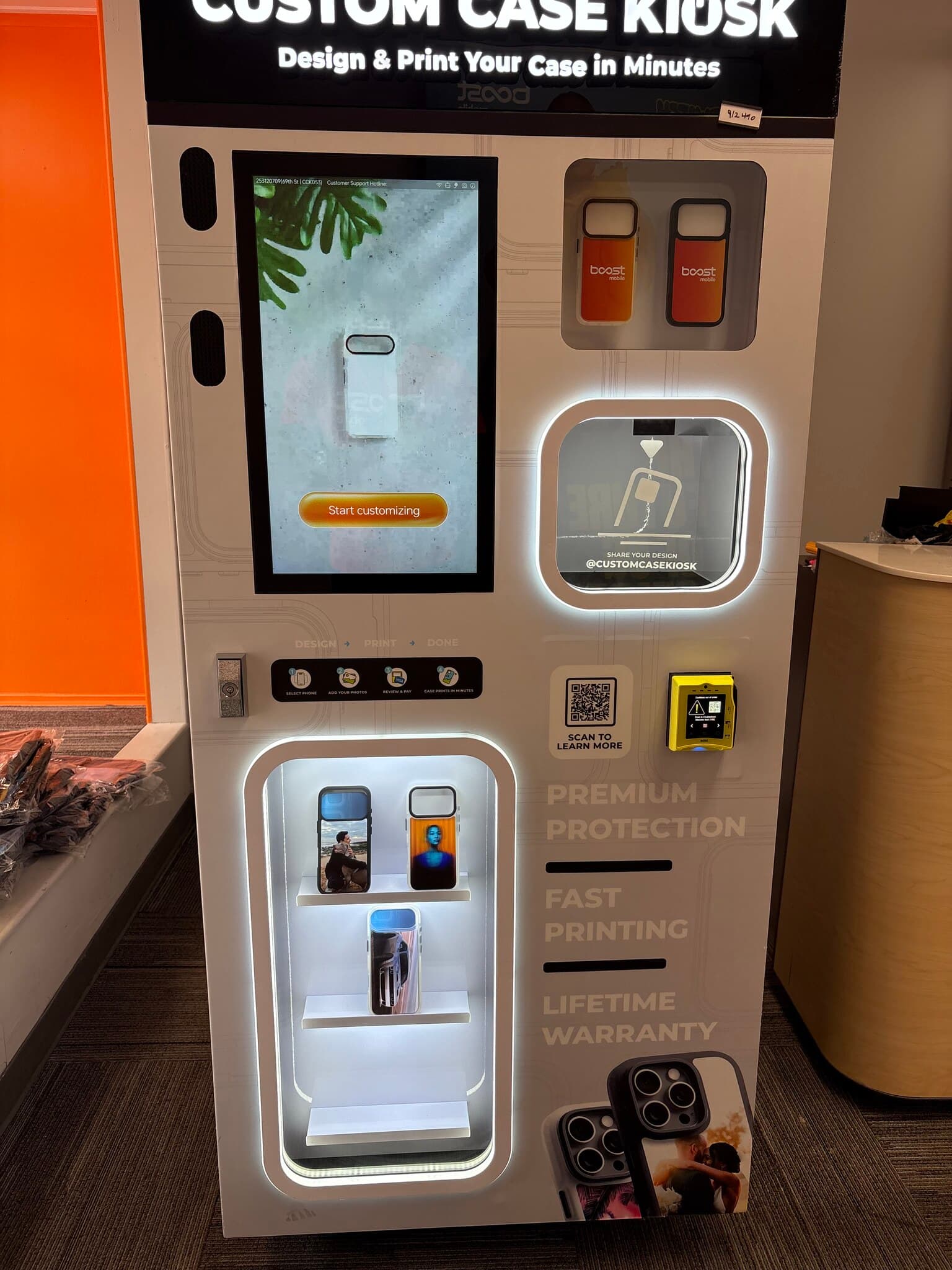 Custom Case Kiosk inside Boost Mobile on South 69th Street in Upper Darby, Pennsylvania — CCK-V4 unit with its lit case display beside the store's orange feature wall